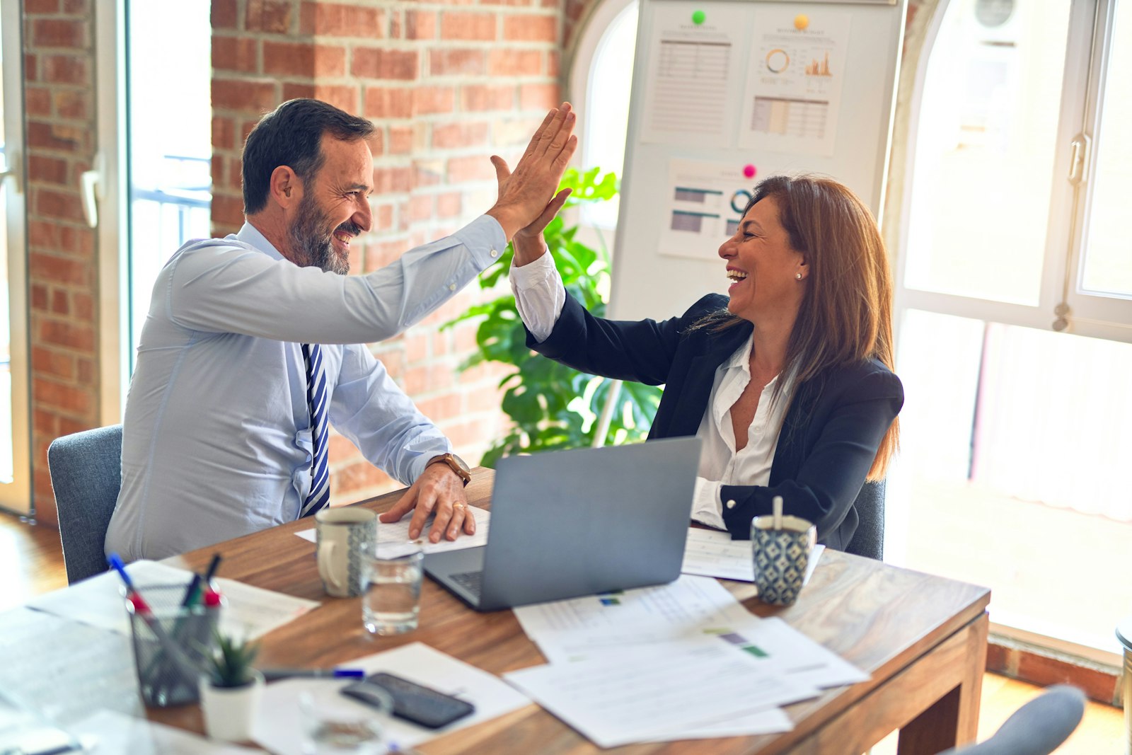 An advisor and client celebrating in a meeting